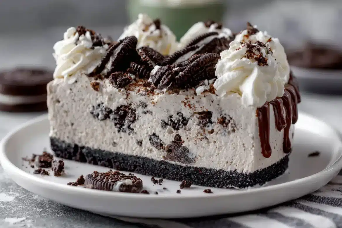No bake cookies and cream mousse cake with layers of fluffy mousse and Oreo cookie crust, topped with whipped cream and cookie crumbles.