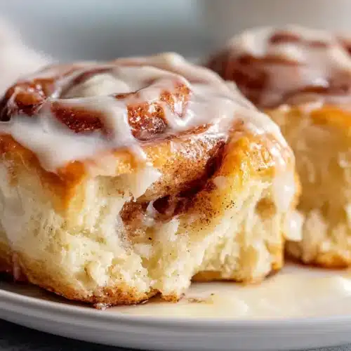 Close-up of soft, fluffy sourdough discard cinnamon rolls with gooey cinnamon sugar swirls and melting cream cheese frosting.